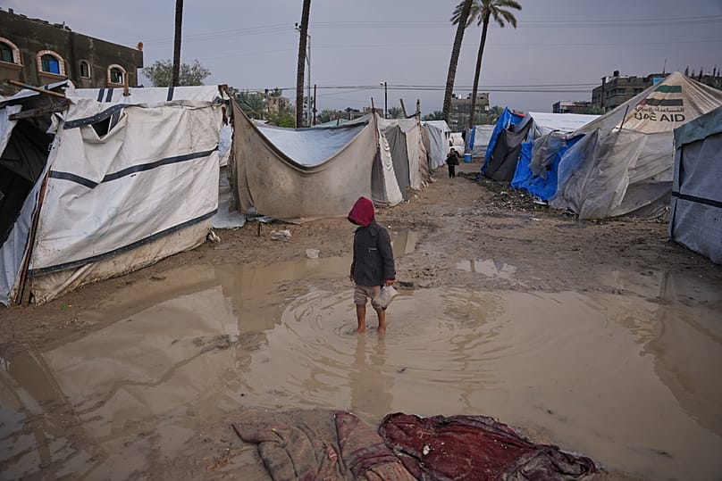 A Palestinian boy walks through an area in a temporary tent camp after heavy rainfall in Deir al-Balah, central Gaza Strip, Friday, Dec. 12, 2025.