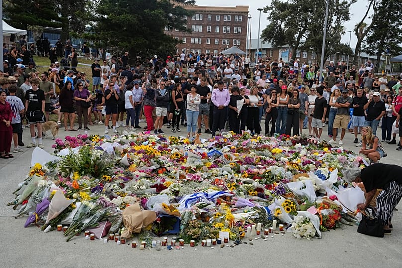 People gather around a tribute for shooting victims outside the Bondi Pavilion at Sydney's Bondi Beach, 15 December, 2025