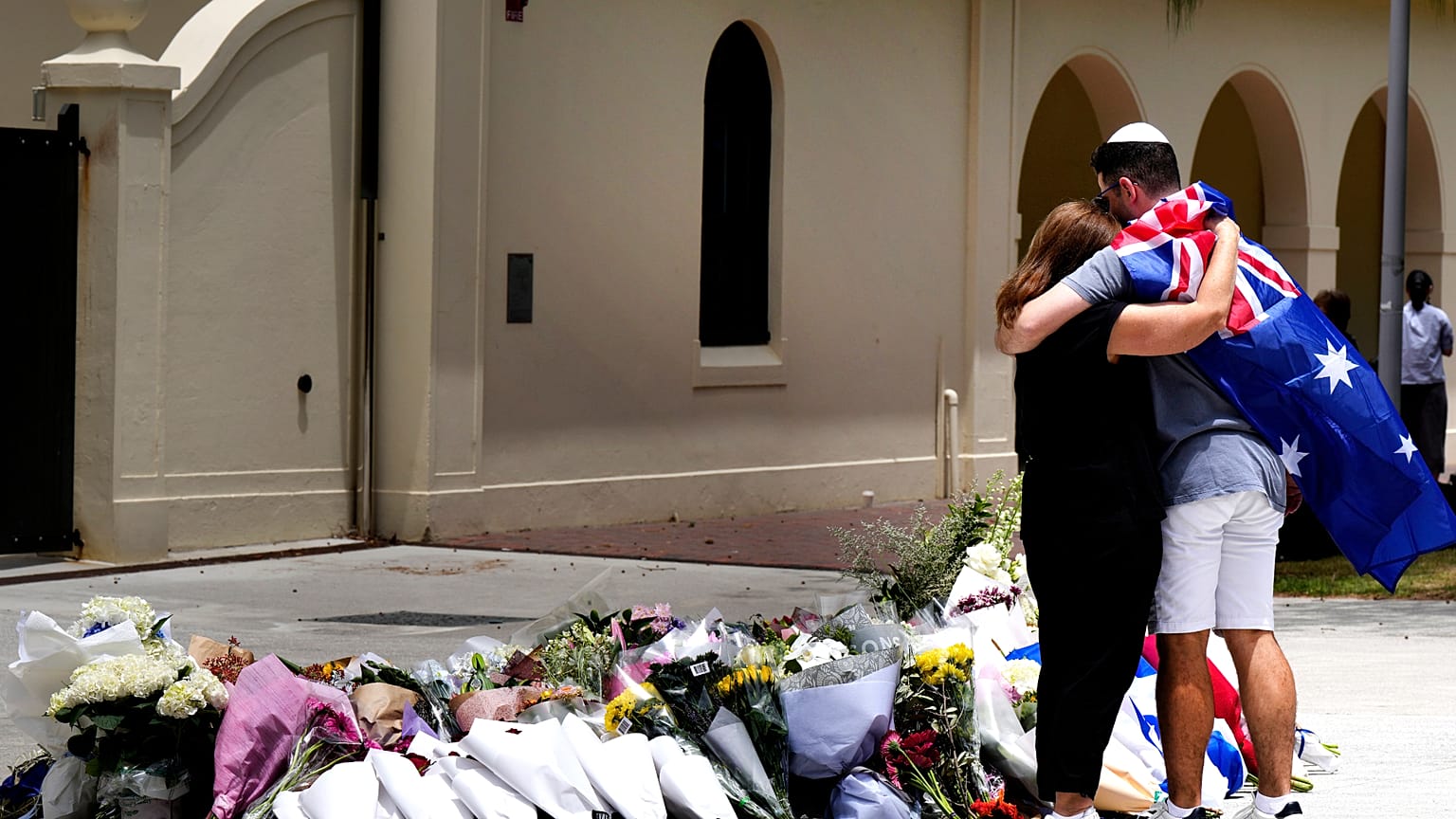 Una pareja deposita flores en un homenaje a las víctimas del tiroteo frente al Bondi Pavilion de Sídney, el lunes 15 de diciembre de 2025.