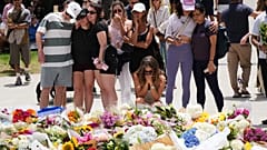 Des gens se rassemblent autour d'un hommage floral croissant aux victimes, devant Bondi Pavilion, à Bondi Beach (Sydney), le 15 décembre 2025, au lendemain d'une fusillade.