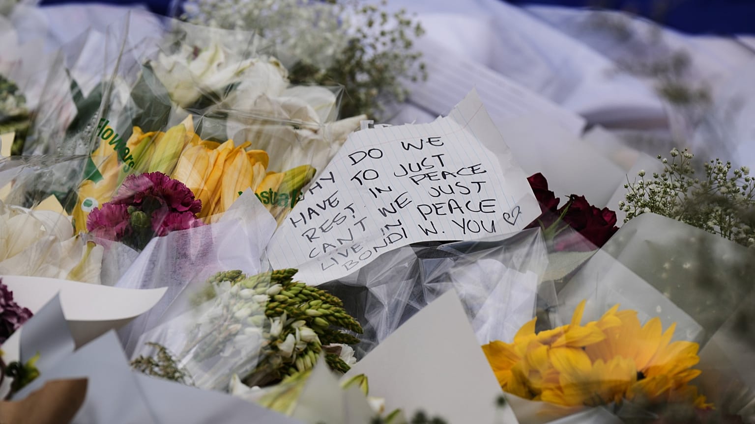 Bei einer Gedenkfeier für die Opfer der Schießerei vor dem Bondi Pavilion am Bondi Beach in Sydney am Montag, 15. Dezember 2025, einen Tag nach der Schießerei, wird eine Notiz an einer Blume befestigt. 