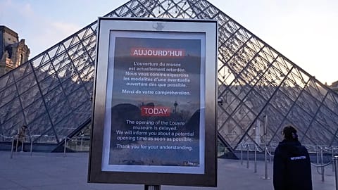 A board advises opening delays outside the pyramid of the Louvre museum in Paris, 15 December, 2025 