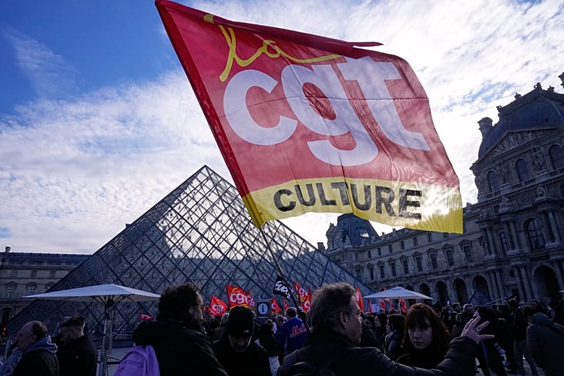 Workers display an union flag outside the Louvre museum after they voted to strike for the day in Paris, 15 December, 2025 