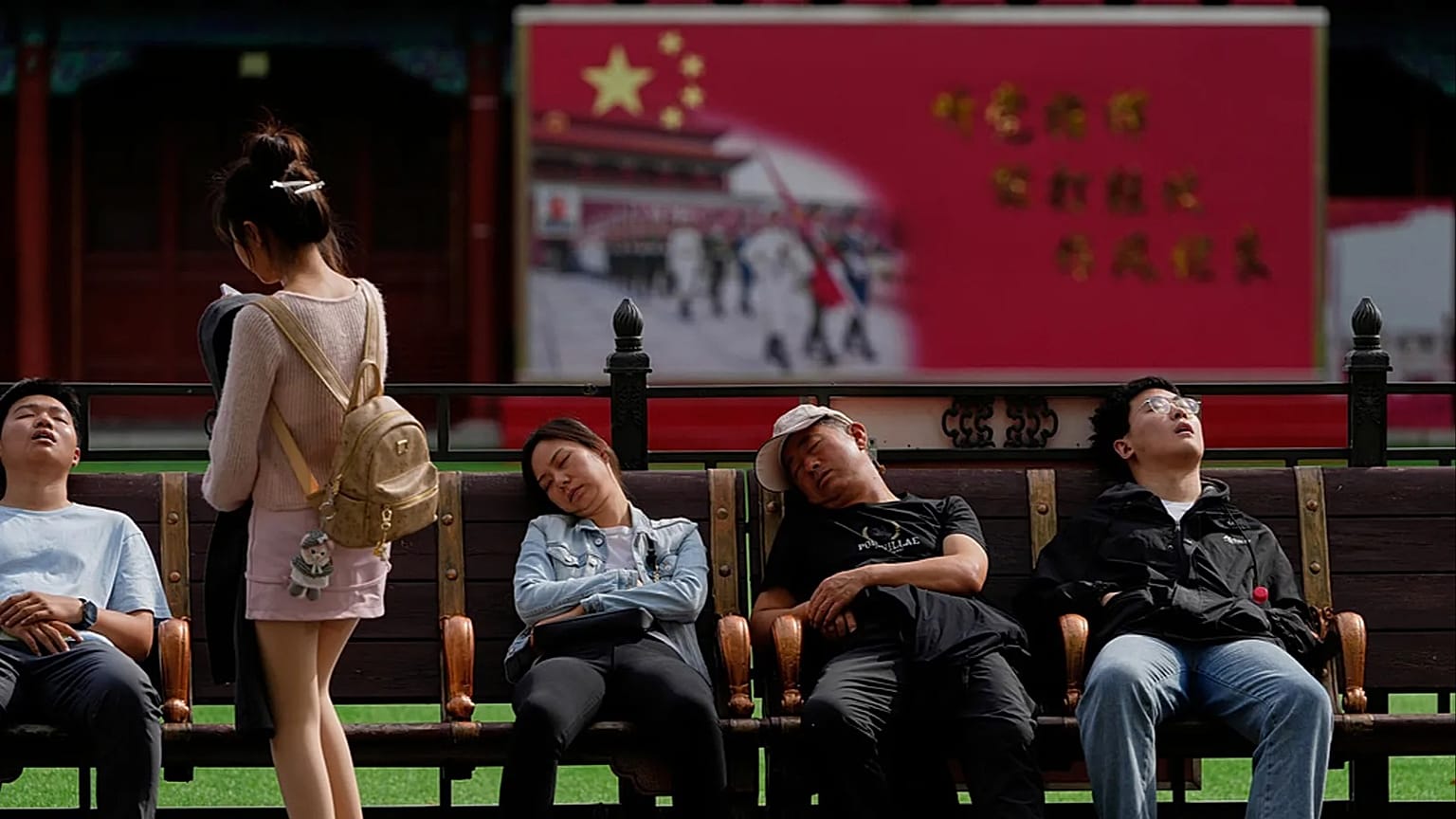 FILE - Tourists nap outside a barrack for honor guards near the Forbidden City during the National Day holidays in Beijing, Wednesday, Oct. 1, 2025.