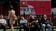FILE - Tourists nap outside a barrack for honor guards near the Forbidden City during the National Day holidays in Beijing, Wednesday, Oct. 1, 2025.