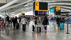 Des passagers passent devant le panneau des départs à l'aéroport d'Heathrow, à Londres, le 28 août 2023.