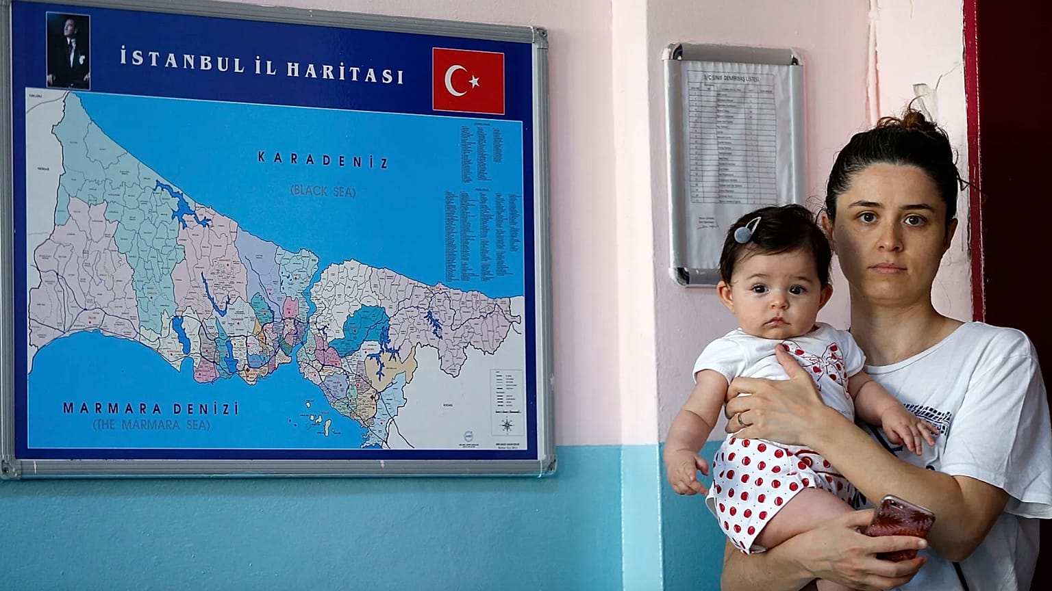 İstanbul'da bir kadın oy vermek için sandıkta beklerken kucağında bebeğiyle poz veriyor, 23 Haziran 2019.