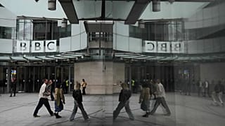 Pedestrians are reflected as they walk outside BBC Broadcasting House in London, 11 November, 2025