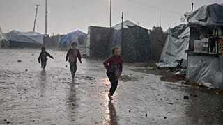 أطفال يركضون تحت المطر قرب مخيم من الخيام في مدينة غزة، الاثنين 15 كانون الأول/ديسمبر 2025.