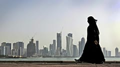 في هذا الصورة المؤرخة في 14 مايو 2010، تسير امرأة قطرية أمام أفق مدينة الدوحة في قطر