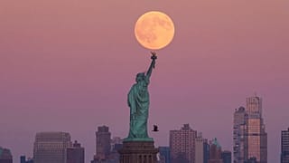 يظهر قمر الحصاد العملاق خلف تمثال الحرية في بروكلين، الاثنين 6 أكتوبر/تشرين الأول 2025، في جيرسي سيتي بولاية نيوجيرسي.