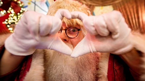 Ein Mann in einem Weihnachtsmannkostüm formt mit seinen Händen ein Herzzeichen auf einem Weihnachtsmarkt in Bukarest, Rumänien, 13. Dezember 2025