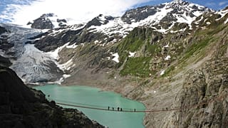 متنزهون يعبرون جسر تريفت الذي أُعيد افتتاحه فوق بحيرة تريفت قرب نهر تريفت الجليدي في وسط سويسرا، في 20 نوفمبر 2025.