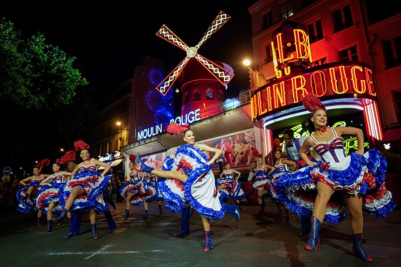 Dancers perform in front of the Moulin Rouge cabaret during the inauguration of the theatre's windmill in Paris, 5 July, 2024