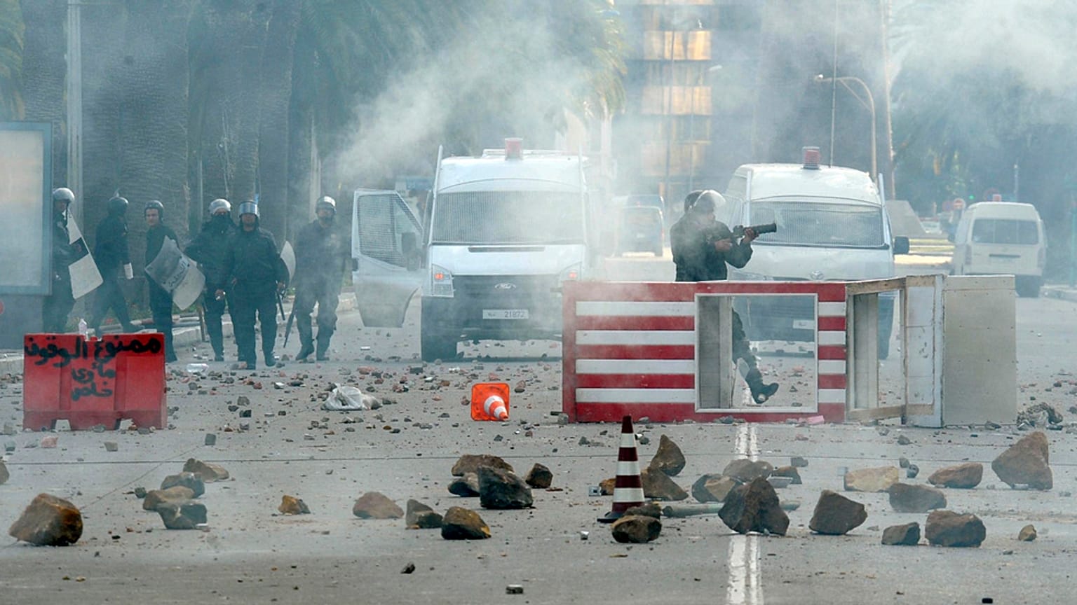 شرطي من قوات مكافحة الشغب التونسية يطلق قنبلة غاز مسيل للدموع خلال اضطرابات في العاصمة تونس، يوم الجمعة 14 يناير/كانون الثاني 2011.