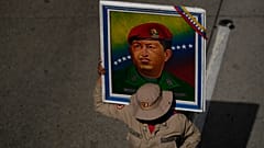 عضو في الميليشيا البوليفارية يحمل ملصقًا للرئيس الراحل هوغو تشافيز خلال تجمع احتفالي بمناسبة عيد ميلاده في كاراكاس، فنزويلا، يوم الاثنين 28 يوليو 2025. 