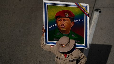 Ένα μέλος της Μπολιβαριανής Πολιτοφυλακής κρατάει μια αφίσα του εκλιπόντος προέδρου Ούγκο Τσάβες κατά τη διάρκεια μιας συγκέντρωσης για τον εορτασμό των γενεθλίων του στο Καράκας της Βενεζουέλας, τη Δευτέρα 28 Ιουλίου 2025. 