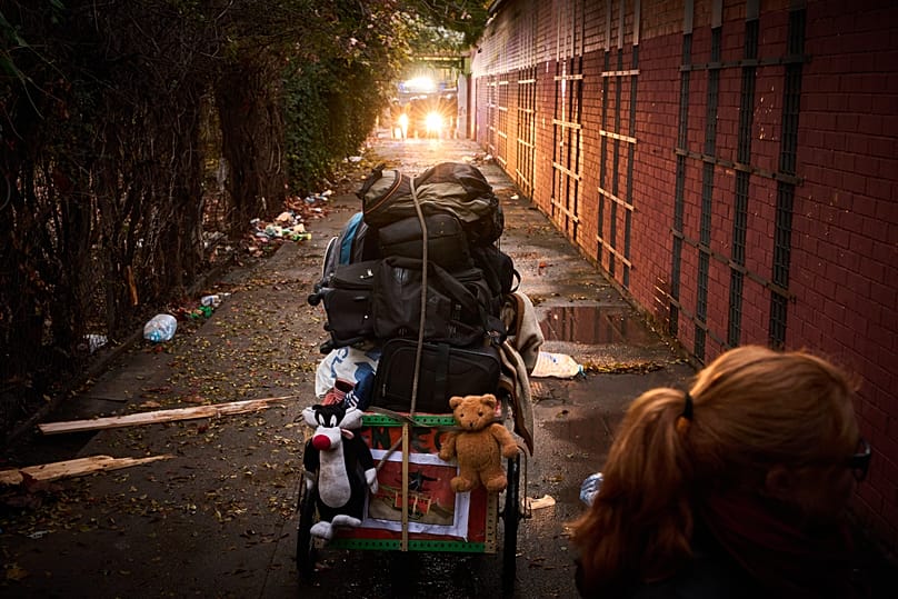 A migrant's belongings are packed before he leaves as police in the background prepares to carry out eviction orders at an abandoned school in Badalona, 17 December, 2025