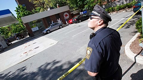 FILE: A Brookline police officer stands at the scene of an FBI investigation at a service station in Brookline, MA., 13 May 2010