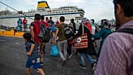 المهاجرون واللاجئون يسيرون لركوب عبّارة متجهة إلى أثينا في جزيرة كوس جنوب شرق اليونان