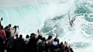 Una folla in cima a una scogliera osserva un surfista durante il torneo Big Wave Challenge di fronte a Praia do Norte, a Nazaré, in Portogallo