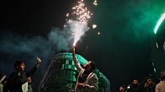رجل يضيء شعلة خلال الاحتفالات بالذكرى السنوية الأولى للإطاحة بنظام بشار الأسد في ساحة الساعة, حمص, غرب سوريا, الإثنين, ديسمبر. 8, 2025.