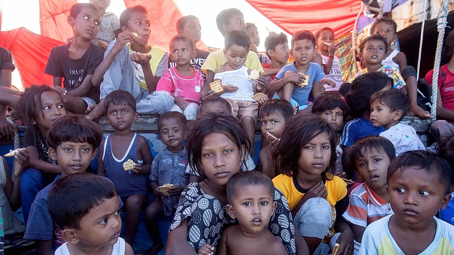 Rohingya refugee children sit on the deck of their boat anchored in the waters near the coast of Labuhan Haji, 22 October, 2024