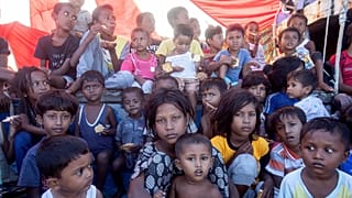 Rohingya refugee children sit on the deck of their boat anchored in the waters near the coast of Labuhan Haji, 22 October, 2024