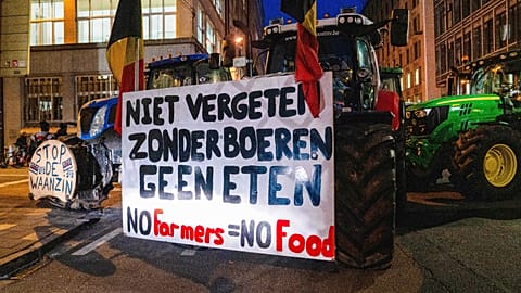A Bruxelles, protesta davanti al vertice UE: un agricoltore guida un trattore con un cartello «Senza agricoltori non c'è cibo». 18 dicembre 2025