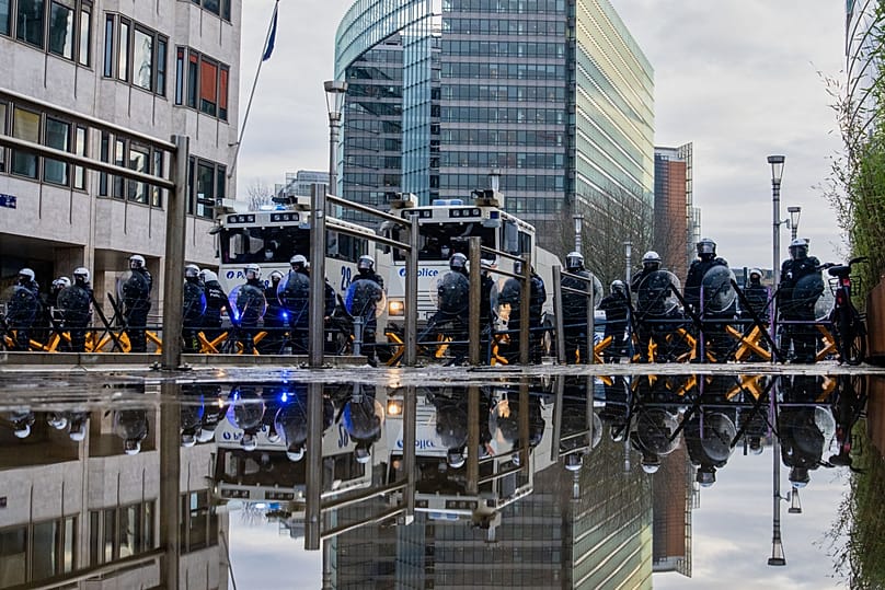 Police stand behind a barrier as European farmers block a road with their tractors during a demonstration outside the EU Summit in Brussels, 18 December 2025