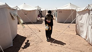 امرأة سودانية نازحة من مدينة الفاشر تحمل طفلها أثناء سيرها بين الخيام في مدينة الدبة بولاية الشمالية في السودان، الأحد 16 نوفمبر/تشرين الثان