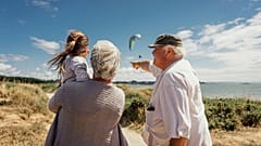 Ein älteres Paar spaziert mit seiner Enkelin am Meer.