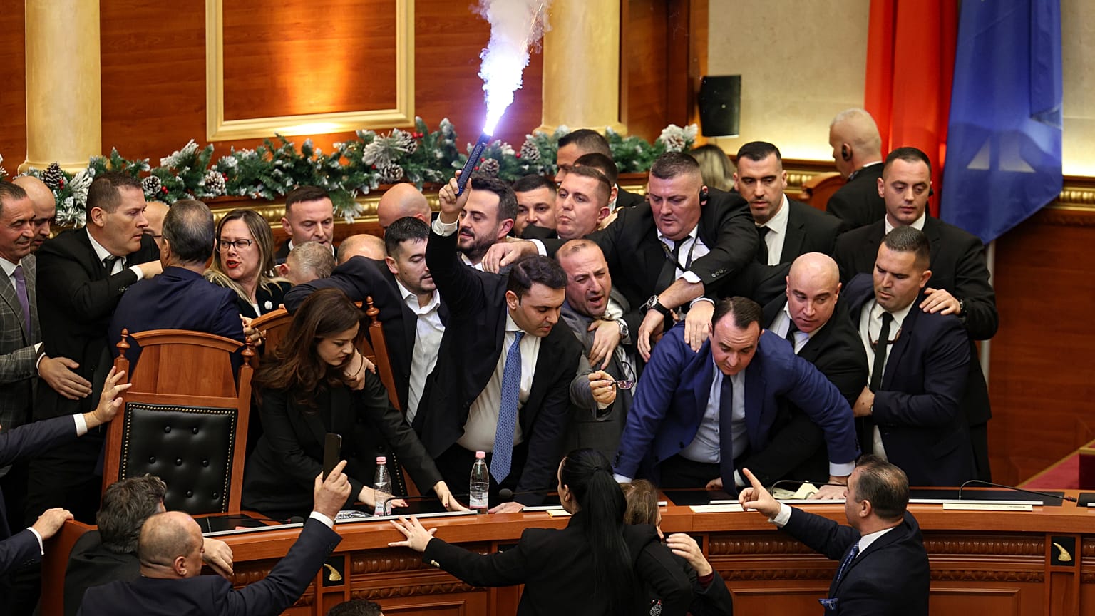 Un deputato del parlamento albanese tiene in mano un bengala nell'aula durante gli scontri tra i deputati del Partito socialista e dell'opposizione