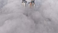 An aerial view of buildings peaking through a dense layer of fog in Sarajevo.