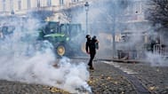 A farmer throws a potato as police fire tear gas during a demonstration of European farmers outside a gathering of European leaders at the EU Summit in Brussels