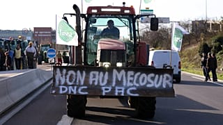 Un agriculteur français conduit son tracteur pour bloquer une route principale lors d'une manifestation contre l'accord commercial du Mercosur avec les pays d'Amérique du Sud,