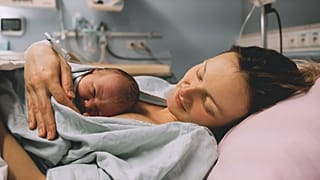 Une mère serrant son nouveau-né dans ses bras à l'hôpital peu après l'accouchement. (Source : Natalia Deriabina, Shutterstock)