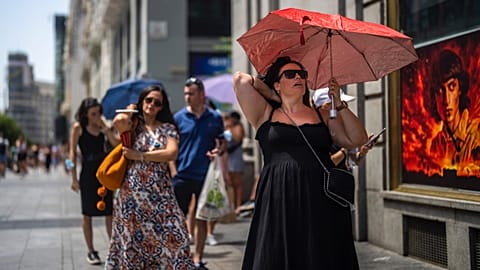 A woman holds an umbrella to shelter from the sun during a hot sunny day in Madrid, Spain, Monday, July 18, 2022. 
