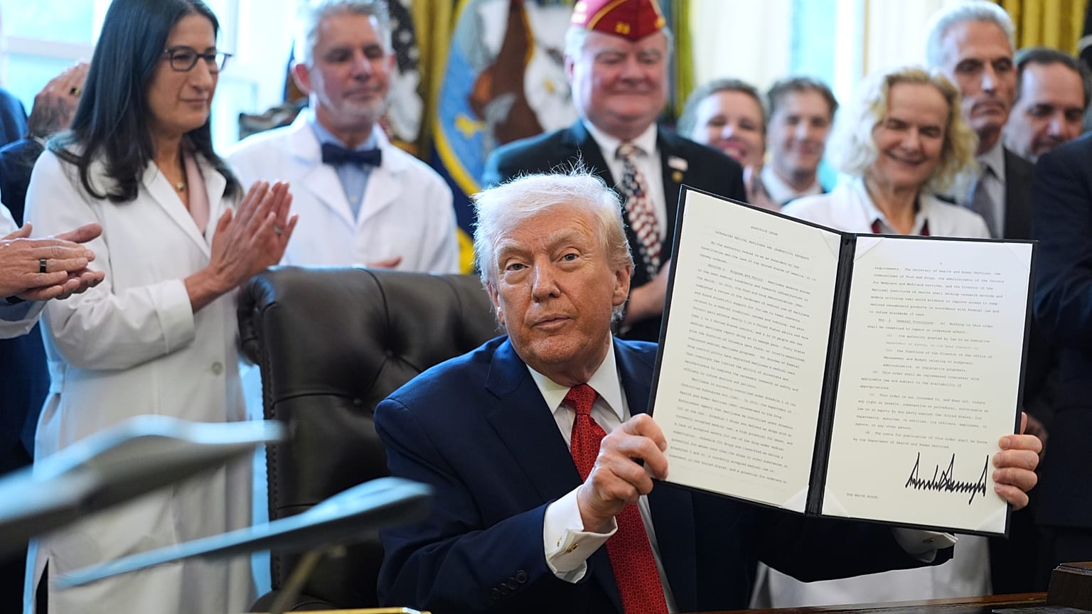 File - President Donald Trump displays an executive order reclassifying marijuana as a less dangerous drug in the Oval Office of the White House, Thursday, Dec. 18, 2025. 