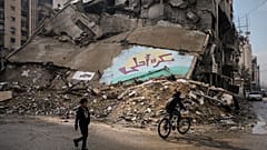 يمشي الفلسطينيون على طول شارع يمرون بجانب مبنى مدمر يحمل جرافيتي باللغة العربية كتب عليه "غد أفضل"، في مدينة غزة، يوم الأربعاء 10 ديسمبر 2025. (صورة أسوشيتد برس/جهاد الشرفي)