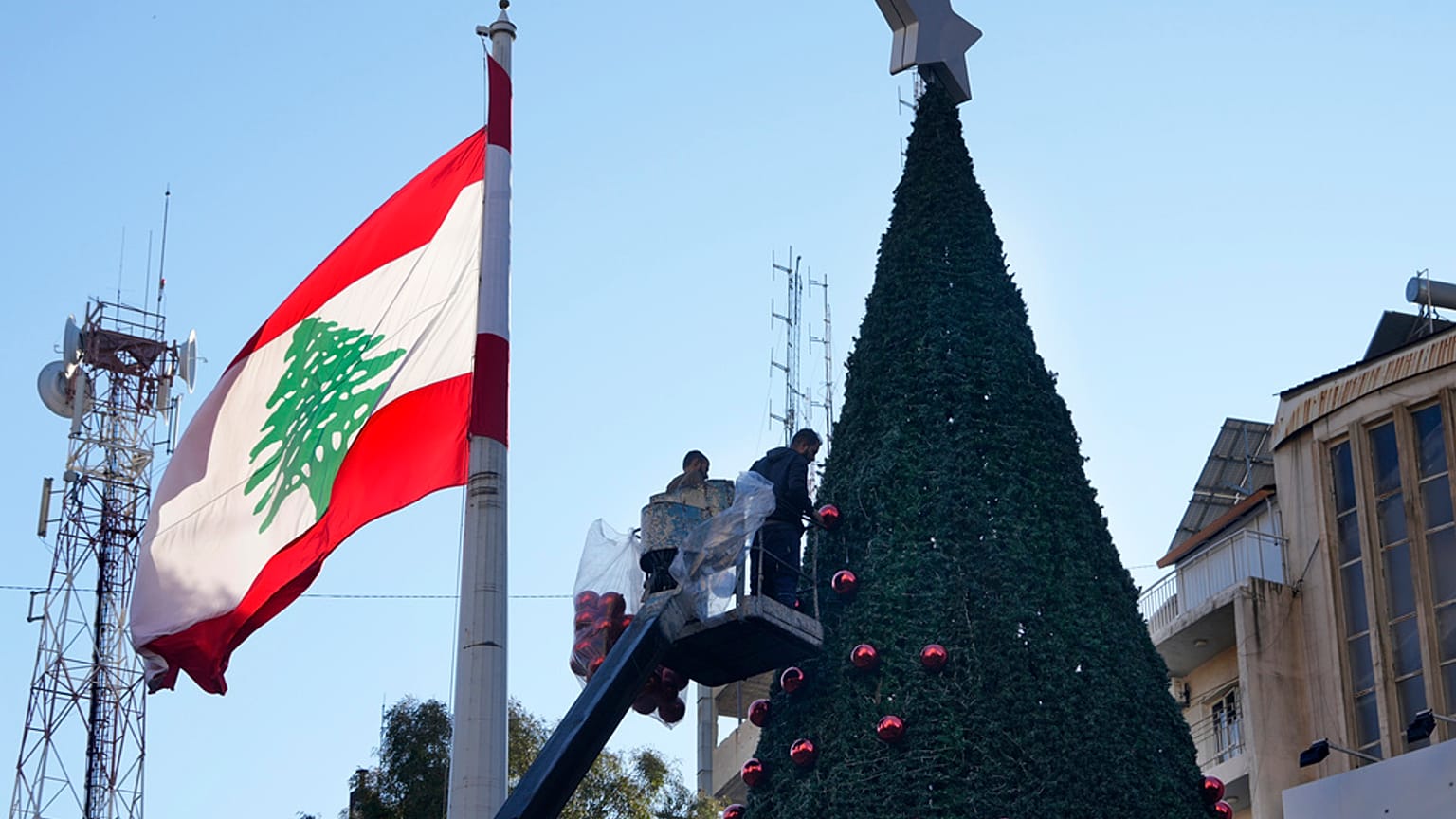 عمال يقفون على رافعة لتزيين شجرة عيد ميلاد عملاقة في حي الأشرفية، في بيروت، لبنان، الأحد 1 ديسمبر 2024.