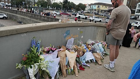 Sydney, domenica 21 dicembre 2025. Un uomo osserva un omaggio floreale sul ponte di Bondi Beach, dopo la sparatoria del 14 dicembre.