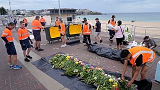 يجمع عمّال أكاليل الزهور ورسائل الدعم والمقتنيات التي تُركت تخليدًا للذكرى أثناء تفكيك نصب تذكاري في سيدني، يوم الاثنين 22 ديسمبر/كانون الأول 2025،