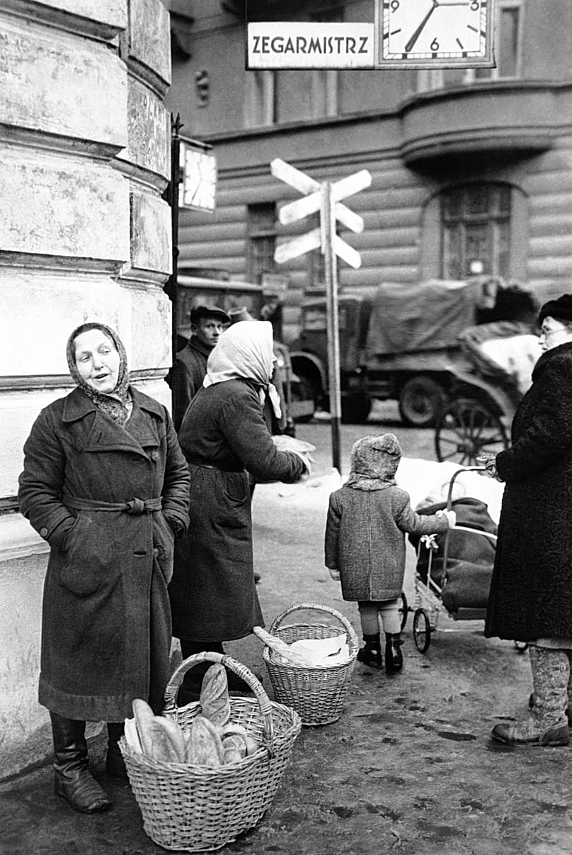 Um vendedor ambulante oferece pão branco de um cesto na esquina de uma das principais ruas de Varsóvia, 17 de dezembro de 1946.