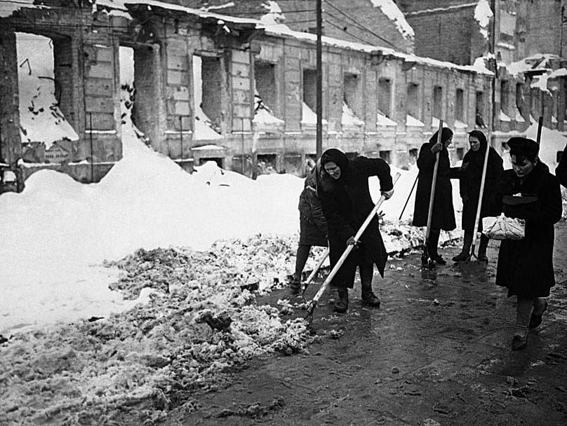 Um grupo de mulheres trabalha arduamente para limpar a neve de uma das ruas rodeadas de ruínas em Varsóvia, a 14 de dezembro de 1946.