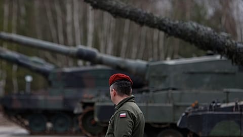 Polonyalı bir asker eğitim sırasında Leopard 2 tanklarının yanında yürüyor