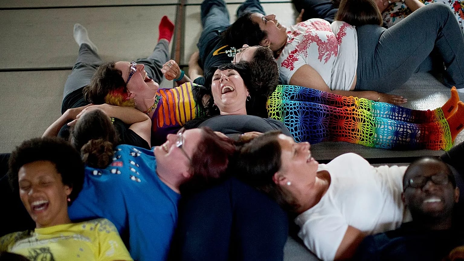 People laugh as they take part in performing a group exercise during a laughter yoga class in St. Albans, England on 9 June 2013