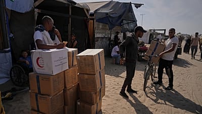 فلسطينيون يحملون صناديق مساعدات غذائية في خان يونس جنوب قطاع غزة، بتاريخ 2 نوفمبر 2025.