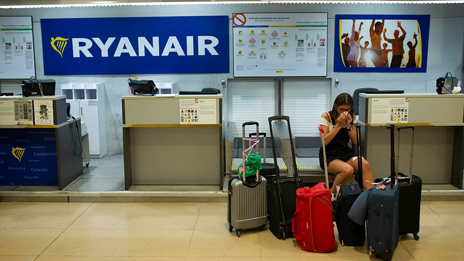 FILE - A Portuguese woman sits at a Ryanair airline check-in desk after her flight to Pisa, Italy, was cancelled on July 25, 2018.