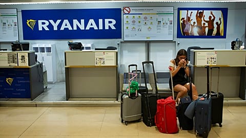FILE - A Portuguese woman sits at a Ryanair airline check-in desk after her flight to Pisa, Italy, was cancelled on July 25, 2018.